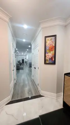 a hallway with white walls and a painting on the wall at Toronto Guest House in Toronto