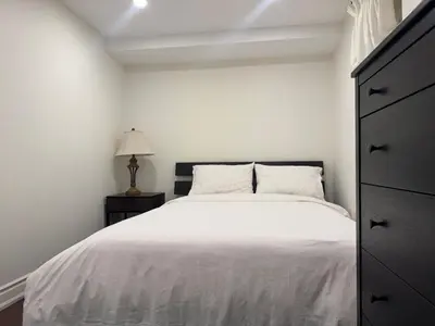 a white bedroom with a bed and a dresser at Stylish 2Bedroom Basement Suite in Oakwood Village in Toronto