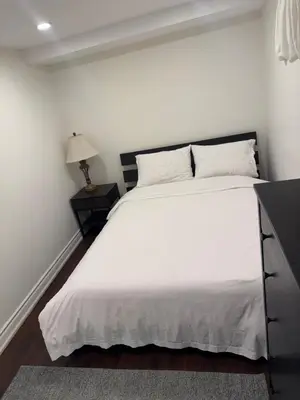 a bedroom with a large white bed with a night stand at Stylish 2Bedroom Basement Suite in Oakwood Village in Toronto