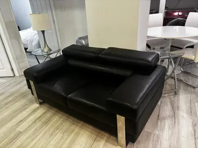 a black leather couch in a room with a table at Ame place in Brampton