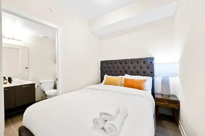 a bedroom with a large white bed with orange pillows at Stylish 3BR Penthouse with Stunning City Views in Toronto
