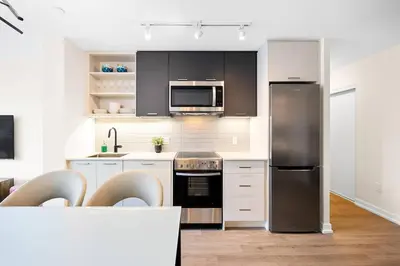 a kitchen with white cabinets and a stainless steel refrigerator at Stylish 3BR Penthouse with Stunning City Views in Toronto