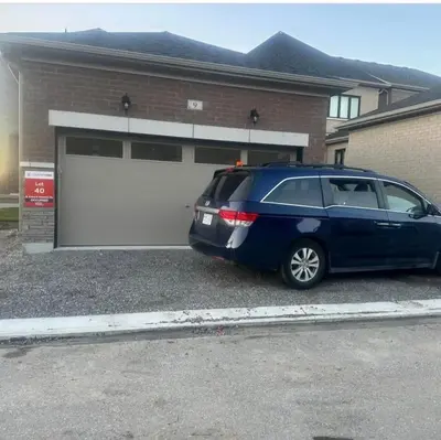 a blue minivan parked in front of a garage at 2 Bedroom private Basement apartment in Markham