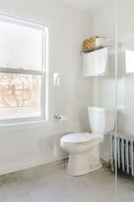 a white bathroom with a toilet and a window at Stylishly Remodeled Queen Victoria Loft in Niagara Falls