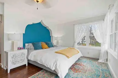 a bedroom with a bed with a blue headboard and a window at Crystal Beach Executive Waterfront Lakehouse in Fort Erie