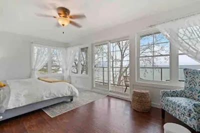 a bedroom with a ceiling fan and a bed and a chair at Crystal Beach Executive Waterfront Lakehouse in Fort Erie