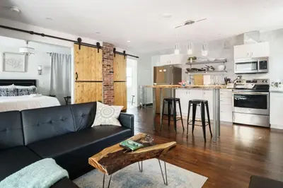 a living room and kitchen with a couch and a table at Wood-Rich Niagara Loft close to Queen Street in Niagara Falls