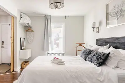 a bedroom with a large white bed with a black headboard at Wood-Rich Niagara Loft close to Queen Street in Niagara Falls