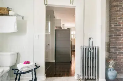 a bathroom with a toilet and a radiator at Wood-Rich Niagara Loft close to Queen Street in Niagara Falls