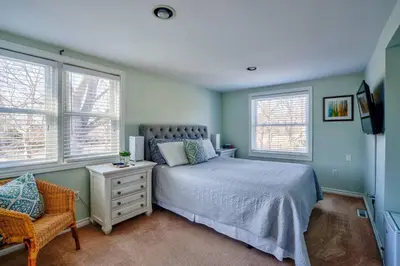 a bedroom with a bed and a chair and windows at Riesling Room Old Town in Niagara on the Lake