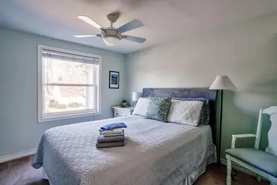 a bedroom with a bed with a ceiling fan and a chair at Merlot Room in Old Town in Niagara on the Lake