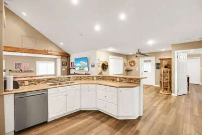 a large kitchen with white cabinets and wooden floors at Family friendly Getaway Steps to the beach in Fort Erie