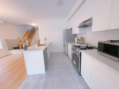 a kitchen with white cabinets and a stove top oven at Vantage stay Modern 4BR townhouse pickering in Pickering