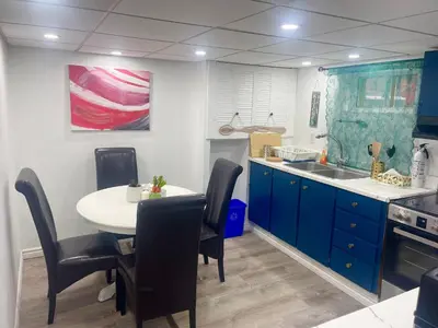 a kitchen with blue cabinets and a table with chairs at Modern & Cozy Basement Suite Lower Unit - 3 rooms -1 King bed - 2 Car Parking in Pickering