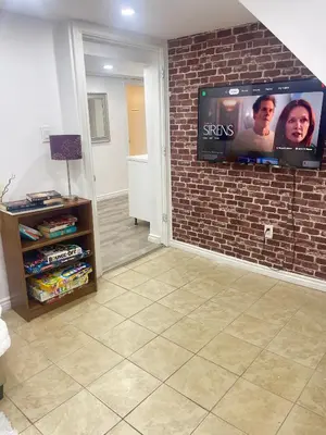 a living room with a tv on a brick wall at Modern & Cozy Basement Suite Lower Unit - 3 rooms -1 King bed - 2 Car Parking in Pickering