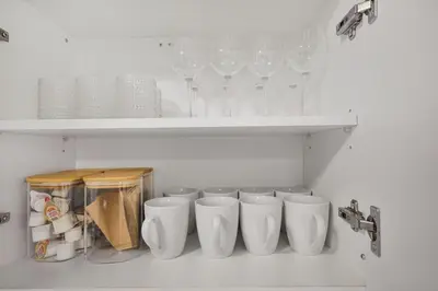 a kitchen with white cups and wine glasses on shelves at 2 BR 1 Bath Apt with Parking and Close to all Amenities in Oshawa
