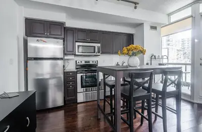 a kitchen with a stainless steel refrigerator and a table with chairs at 1 Bedroom plus Den Condo Garden View Fort York Downtown Toronto in Toronto