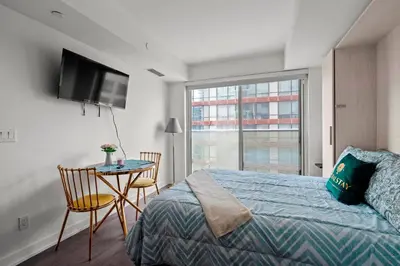 a bedroom with a bed and a table and a television at Modern Studio Condo Yonge Street Downtown Toronto in Toronto