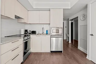 a kitchen with white cabinets and a clock on the wall at Modern Studio Condo Yonge Street Downtown Toronto in Toronto