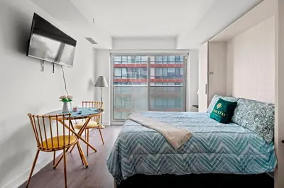 a bedroom with a bed and a desk and a window at Modern Studio Condo Yonge Street Downtown Toronto in Toronto