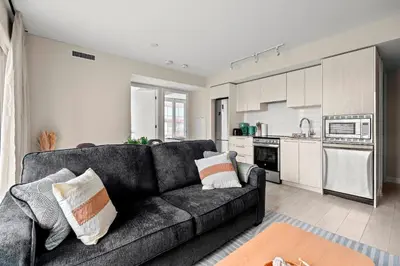 a living room with a couch and a kitchen at Panoramic 2 Bedroom plus Den Condo Yonge Street Downtown Toronto in Toronto