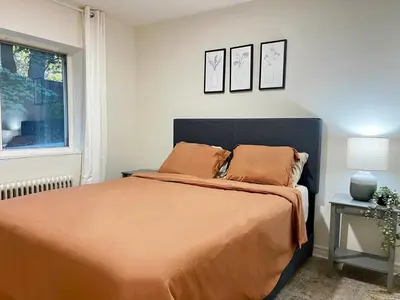a bedroom with a bed with orange sheets and a window at Toronto Upper Beaches Apartment in Toronto