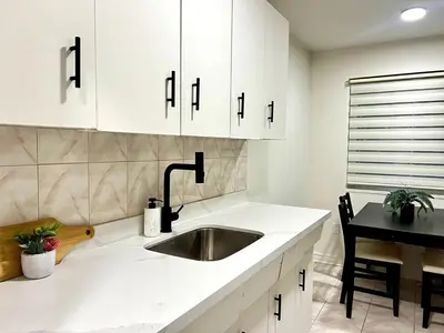 a kitchen with white cabinets and a sink at Toronto Upper Beaches Apartment in Toronto