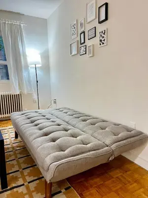 a large tufted bed in a room with a wall at Toronto Upper Beaches Apartment in Toronto