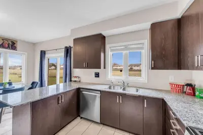a kitchen with brown cabinets and a sink and windows at Luxury Home Mins from Waterfall next to Transit in Niagara Falls