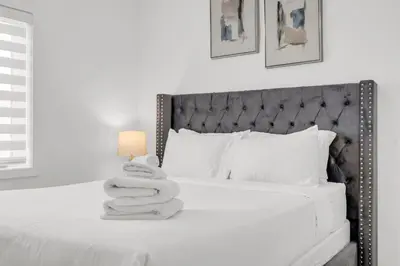 a white bedroom with a bed with towels on it at 5 Mins to the Falls Brand New Home in Niagara Falls