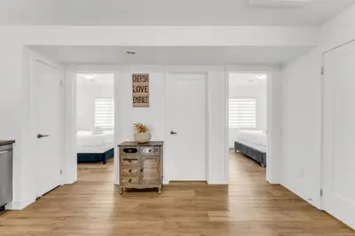 a white room with two beds and a wooden table at 5 Mins to the Falls Brand New Home in Niagara Falls