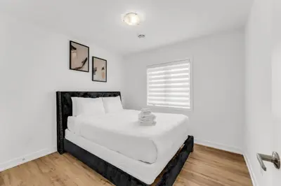 a white bedroom with a large white bed in it at 5 Mins to the Falls Brand New Home in Niagara Falls