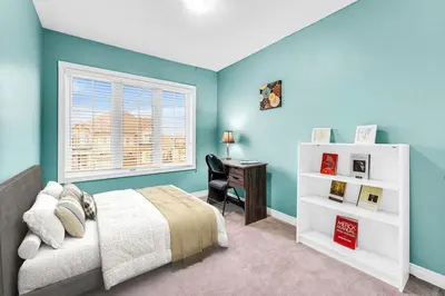 a bedroom with blue walls and a bed and a desk at Charming Home with Airport and Toronto Nearby in Brampton