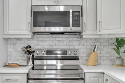 a kitchen with a stainless steel stove and a microwave at Pristine Home 5 min walk to Clifton Hill in Niagara Falls