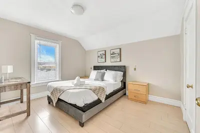 a bedroom with a bed and a desk and a window at Pristine Home 5 min walk to Clifton Hill in Niagara Falls