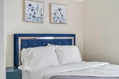 a bed with a blue headboard and two pictures on the wall at Pristine Home 5 min walk to Clifton Hill in Niagara Falls