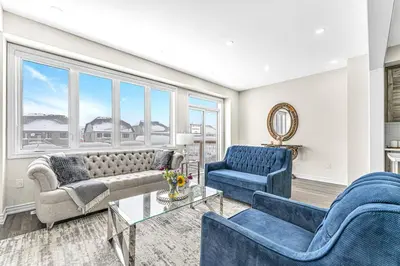 a living room with blue furniture and large windows at Designer Home in Niagara Falls in Thorold