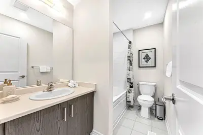 a white bathroom with a sink and a toilet at Designer Home in Niagara Falls in Thorold