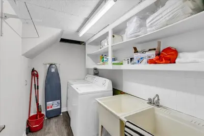 a small white laundry room with a washer and a sink at War of 1812 Battlefield Home by Falls in Niagara Falls