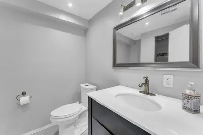 a bathroom with a sink and a toilet and a mirror at Spacious 6BR Getaway Sleeps 16 Yard and Parking in Brampton