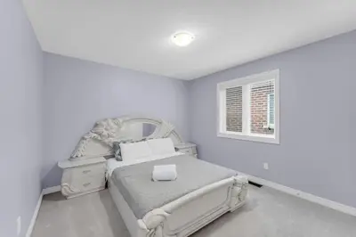 a white bedroom with a bed and a mirror at Bright and Stylish Family Home Near Niagara Falls in Thorold