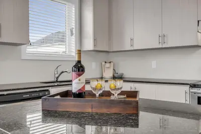 a bottle of wine and two glasses on a counter in a kitchen at Bright and Stylish Family Home Near Niagara Falls in Thorold