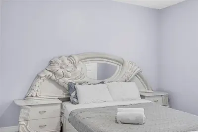 a white bed with a mirror on top of it at Bright and Stylish Family Home Near Niagara Falls in Thorold