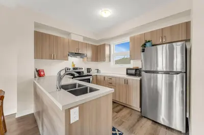 a kitchen with a stainless steel refrigerator and wooden cabinets at Stylish Niagara Falls Getaway with Rooftop City Views in Niagara Falls