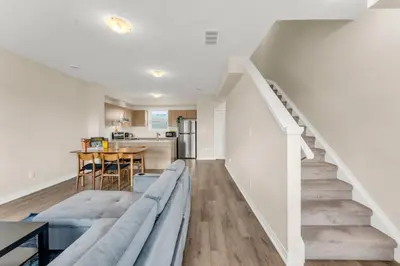 a living room with a couch and a staircase at Stylish Niagara Falls Getaway with Rooftop City Views in Niagara Falls