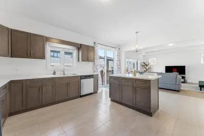 a large kitchen with wooden cabinets and a living room at Luxury New Home By Niagara Fall in Fonthill