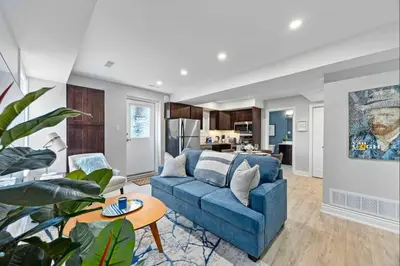 a living room with a blue couch and a kitchen at Casa Hotel Stylish Modern Family Suite with Patio in Toronto