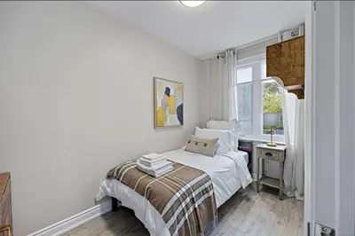 a white bedroom with a bed and a window at Casa Hotel Stylish Modern Family Suite with Patio in Toronto