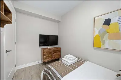 a bedroom with a bed and a flat screen tv at Casa Hotel Stylish Modern Family Suite with Patio in Toronto