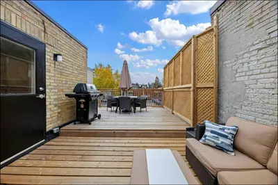 a wooden deck with a grill and a table and chairs at Casa Hotel Stylish Modern Family Suite with Patio in Toronto